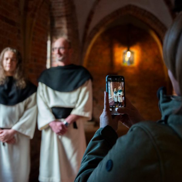 Iemand neemt een foto van twee bezoekers die zich als kruisheren verkleden.