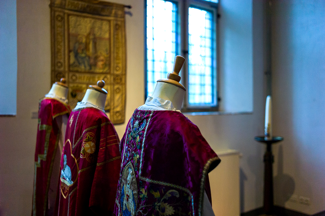 Kerkelijke kleding staat opgesteld in een tentoonstellingsruimte.