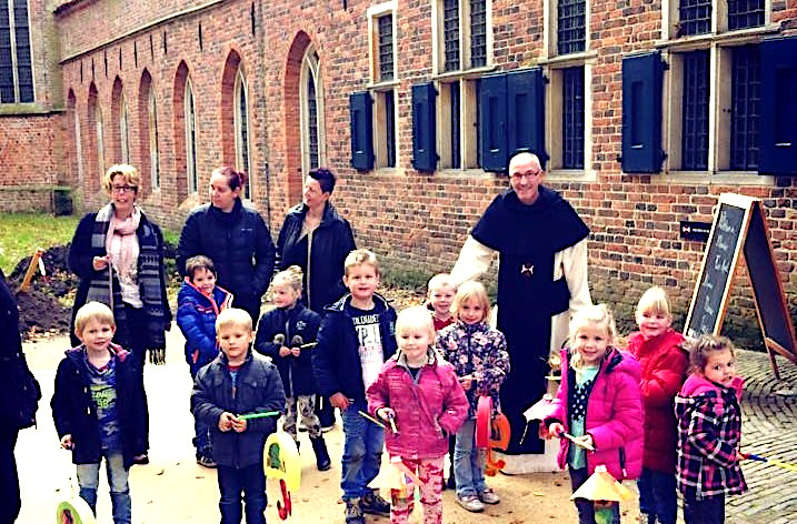 Een groep kinderen staat met hun lampion bij de ingang van het Klooster.